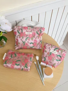 Close-up detail of pink floral jacquard fabric cosmetic bag with delicate embroidery and brand tag.