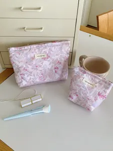 Detailed view of pink floral cosmetic pouch set with elegant fabric label and lifestyle props.