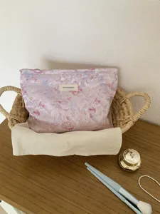 Close-up detail of the stylish floral cosmetic bag in a woven basket on a wooden table.