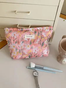 Pink embroidered floral cosmetic bag detail shot, portable makeup storage pouch for travel.
