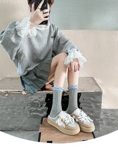 Women grey mid-tube socks with cable knit design and blue ruffles paired with casual shoes detail.