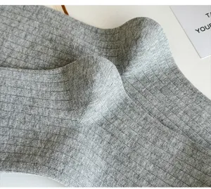 Close-up view of grey ribbed knit long socks showing fine texture and soft fabric detail.