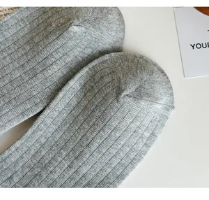 Close-up detail of grey ribbed knit long socks texture, soft cotton blend fabric style.