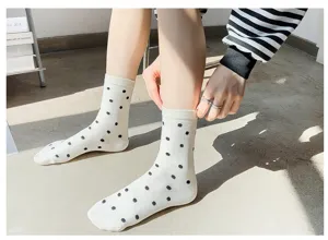 Gros plan de chaussettes mi-hautes blanches mignonnes pour femmes aux pois noirs classiques.
