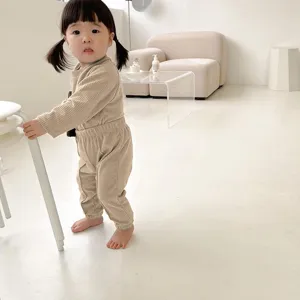 Detailed view of the ribbed toddler two-piece outfit worn by a child in a minimalist room.