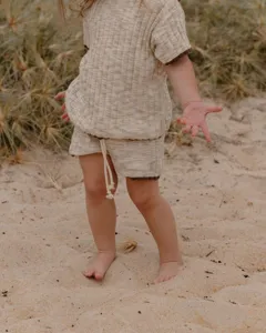 Détail ensemble haut et short manches courtes tricot bébé, style plage contraste doux.