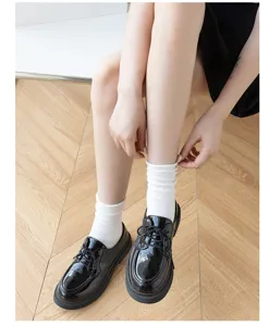 Gedetailleerd uitzicht op witte dames mesh sokken en zwarte schoenen in lente-ontwerp.
