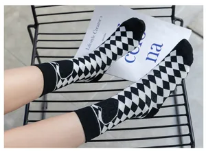 Vue détaillée de chaussettes à motif argyle noir et blanc avec cœur sur une chaise.