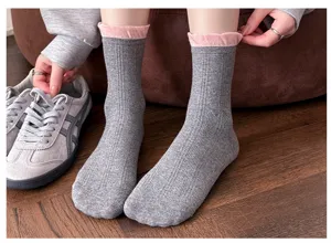 Vue détaillée de chaussettes mi-mollet en coton gris avec bord volanté rose et texture subtile.