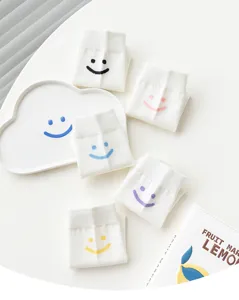 Chaussettes blanches en coton pour femmes avec des motifs de visages souriants colores.