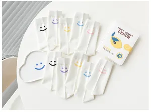 Chaussettes montantes blanches style japonais pour femmes avec jolis motifs souriants colorés.