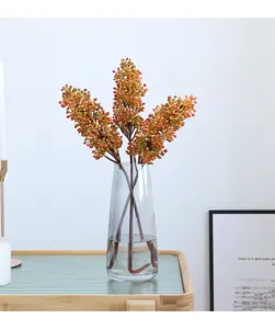 Artificial rice berry flower branch in glass vase, elegant home decor showroom display piece.