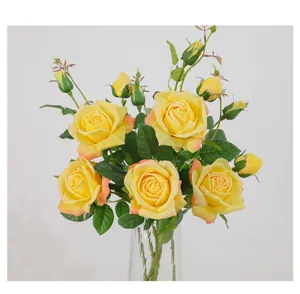Closeup of artificial vintage yellow roses bouquet in clear glass vase for elegant home decor.