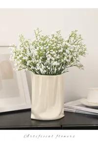 Artificial gypsophila plastic flowers in white ceramic vase for home wedding decor detail