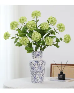 Kunstmatige groene hortensiabloemen in blauwwitte porseleinen vaas voor huisdecoratie details.