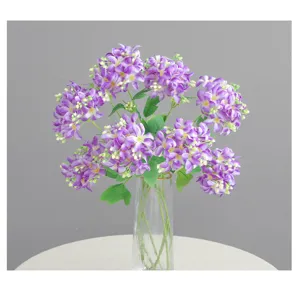Dettaglio in primo piano del bouquet di ortensie artificiali viola con bacche e foglie verdi.