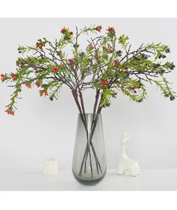Artificial berry branches in glass vase, realistic faux red and blue fruit stems for decor.