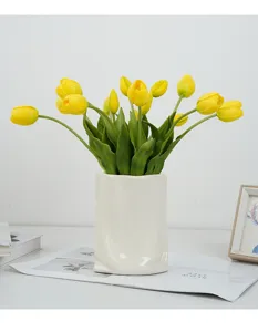 Detailed view of artificial yellow tulip bouquet in white ceramic vase, perfect desk decor.
