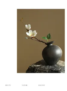 Black ceramic vase with artificial magnolia flower branch zen home decor detail view
