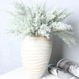 Detailed close-up shot of artificial pine branches and foliage placed in a rustic ceramic vase.