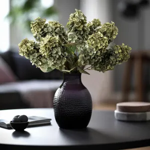 Bouquet di ortensie artificiali in vaso viola scuro, dettaglio di arredamento per la casa.