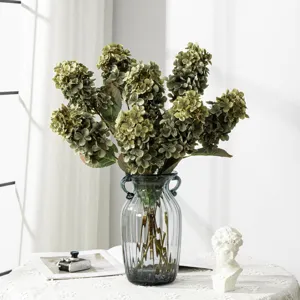 Dettaglio ramo di fiore di ortensia verde artificiale in elegante vaso di vetro per decoro casa.