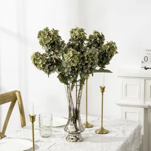Vista dettagliata di bouquet di ortensie verdi artificiali in vaso di vetro argentato.