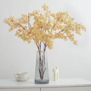 Branche de fleurs artificielles avec vase en verre pour décoration, style minimaliste.