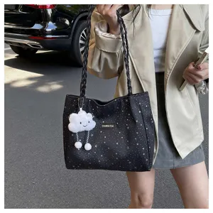 Vista dettagliata della borsa tote con stampa di stelle e ciondolo a nuvola con manici intrecciati.