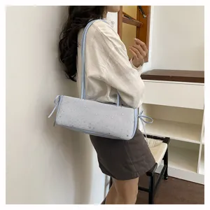 Detailed view of a light blue cylindrical shoulder bag featuring star patterns and side ties.
