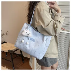 Dettaglio borsa shopper azzurra con stelle, grazioso ciondolo in peluche a forma di nuvola.
