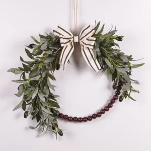Artificial olive branch wreath detail, featuring striped bow and wooden beads for decor.