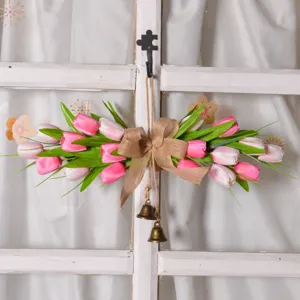 Detailed view of artificial tulip flower wreath with rustic burlap bow and hanging brass bells.