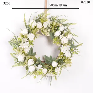 Close-up of artificial white rose wreath showing green leaves and vine base for decor.