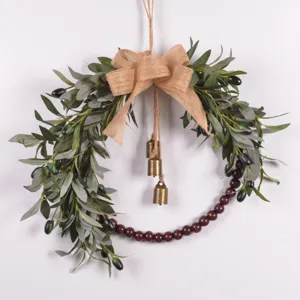 Artificial olive leaf wreath detail with wooden beads, burlap bow and brass bells.