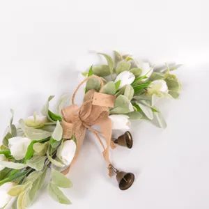 Detalle de cerca de la guirnalda de flores de tulipán artificial con lazo de arpillera y campanas.