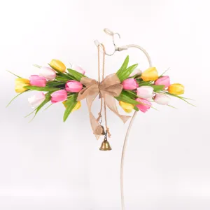 Detailed view of artificial tulip flower swag with burlap bow and brass bells, ideal for decor.