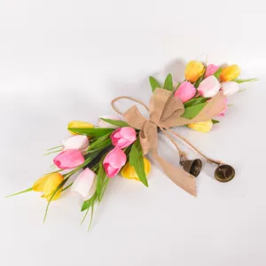 Detailed view of artificial tulip flower wreath with burlap bow and small bells for decor.