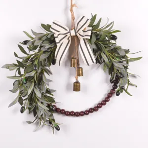 Detailed view of the artificial olive leaf wreath featuring a bow, hanging bells, and wooden beads.