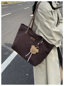 Detailed view of the stylish canvas tote bag with cute bear pendant in daily commute.