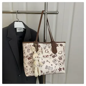 Vista dettagliata della grande borsa a tracolla tote con ciondolo coniglietto e stampa graffiti.