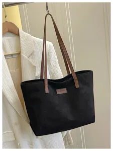 Detailed view of large black tote bag with brown straps, commuter style casual handbag.