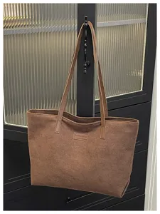 Brown tote bag detail view, showing the durable shoulder straps and textured surface material.