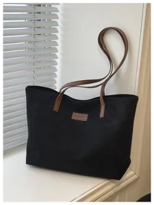 Detailed view of the black casual tote bag featuring brown straps and front logo patch.