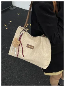 Vista dettagliata della borsa tote trapuntata vintage con simpatico ciondolo orsetto e stile.
