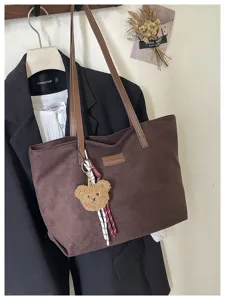 Detailed view of the brown corduroy tote bag featuring handle and cute bear charm pendant.