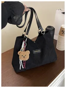 Dettaglio borsa shopper in camoscio nero, design casual con portachiavi orsetto di peluche.