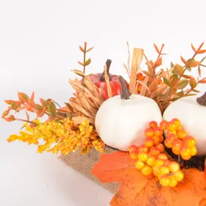Close-up detail of artificial autumn pumpkin maple leaves and berries burlap centerpiece decor.