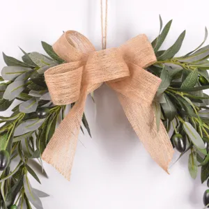 Close up of artificial olive branch wreath with rustic burlap bow for home decor.