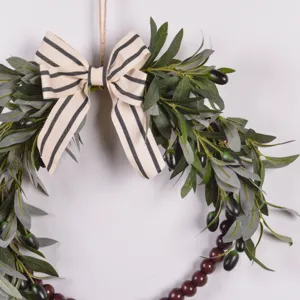 Detail view of artificial olive leaf wreath featuring striped bow and dark wooden beads.
